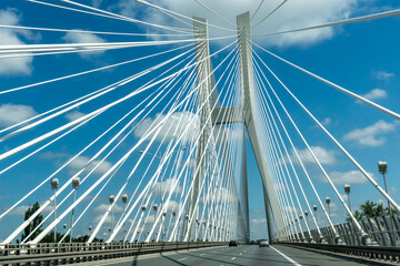 Beautiful suspension bridge with cars passing over it under a bright blue sky with white clouds. Wroclaw. Poland. High quality photo