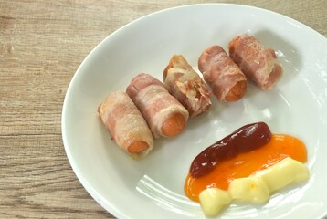 pork sausage roll up bacon dipping mayonnaise and chili sauce with ketchup arranging on plate