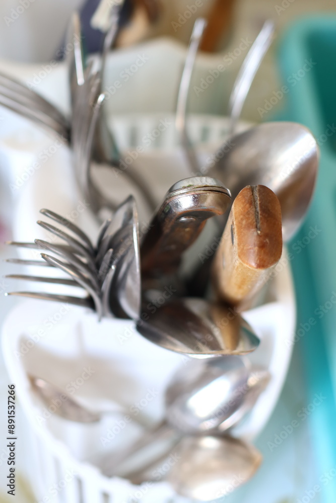 Poster a collection of forks and spoons in a bowl, suitable for use in kitchen or dining setting.