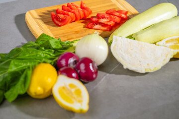 There are vegetables on a table next to a cutting board
