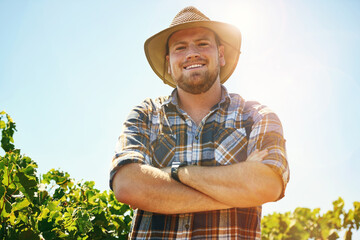 Farmer, man and arms crossed in portrait with smile at vineyard for growth, development or progress in summer. Person, agriculture and grapes with sustainability, happy and quality control in Spain