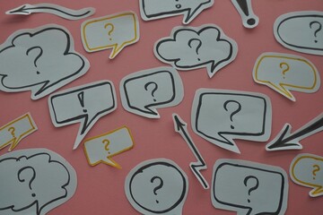 top view of of black question and exclamation mark on white speech bubble on a pink background.