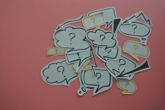 top view of of black question and exclamation mark on white speech bubble on a pink background.
