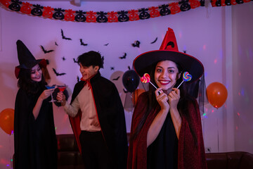 Friends celebrating Halloween with costumes and festive drinks. Asian man and women. Looking at...