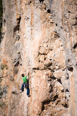 Fototapeta premium A rock climber climbs to the top along a difficult route. 