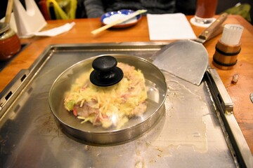 鉄板のお好み焼きに蓋をしてじっくり焼く
