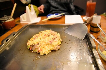 お好み焼きの具を鉄板の中央にまとめる男性
