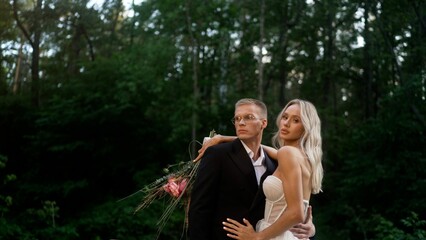 Young wedding couple hugging. The groom hugs the bride in nature, against the backdrop of the forest.