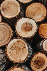 Close up of round wood stacked together, cut off tree trunks, light brown in color