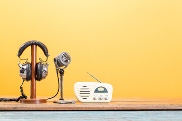 Retro radio, old microphone, headphones from circa 60s front yellow background. Vintage style...