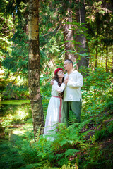 Couple in traditional Slavic clothing embraces in a serene forest