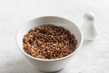 Bowl with boiled buckwheat on a white background. healthy homemade food