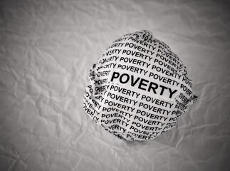 Crumpled paper ball with words Poverty on a crumpled white paper background. Black and white.