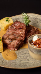 A delicious fillet of beef, perfectly garnished with rosemary and served in an appetising mustard sauce accompanied by a side of parsley potatoes and a dressing in a bowl: a truly delicious combinatio