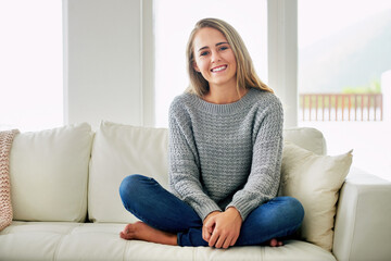 Fototapeta premium Portrait, crossed legs and woman on couch, relax and happiness with peace, resting and calm in living room. Face, apartment and person on sofa, cheerful and comfortable with weekend break in house