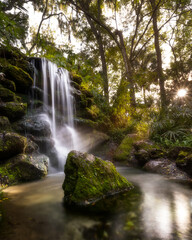 Beautiful waterfall with moss covered rocks and evening sun peeking through trees at Rainbow Springs State Park, Florida