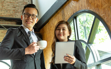 Executive business managers office team working using 
computer drinking hot coffee. Two mid aged colleagues company board after discussing digital strategy at modern meeting room. Copy space.