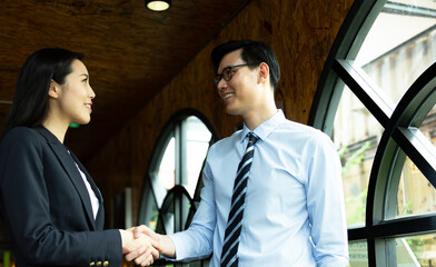 Young Financial consultant or real estate agent at the luxury office shaking hands with Gorgeous customer after having a deal or make agreement. Business and working concept.