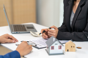 A real estate agent talks with his client regarding a home purchase contract, concept for real...