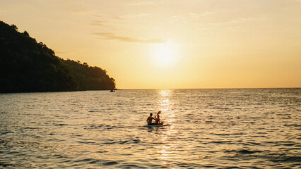 Fototapeta premium Kayak on the beach at sunset. Thailand. Exotic Sunset Beach and Calm Seascape for Summer. Couple kayaking at sunset by the sea. Canoe on the ocean beach during the amazing sunset.