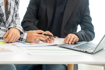 Business People discussion at Table using variety of electronic Devices on grey Office Table Computer, Tablet, printed Paper Charts