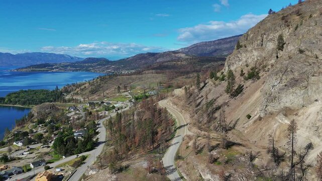 Aerial view (tilt up / pan right) of Westside Road near Okanagan Lake during a spring season in West Kelowna, British Columbia, Canada