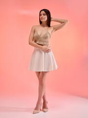 a beautiful woman in a knitted summer top poses on a monochrome colored background smiling happily