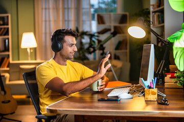 Indian asian  young student or businessman using laptop with coffee, books, smartphone, headphone.