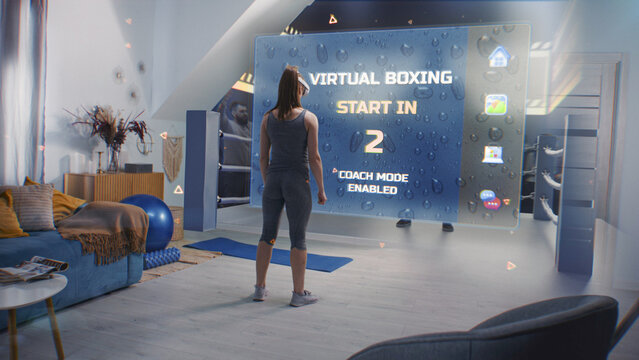 Female athlete wearing augmented reality headset starts boxing training. VR screen shows virtual coach and interface of AR boxing app. Metaverse futuristic home gym with AI technologies. VFX animation - Powered by Adobe