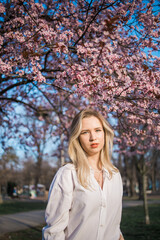 Woman with cherry flowers surrounded by blossoming trees copy space. Beauty and seasonal change and spring bloom season concept.