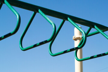 Closeup of triangle style monkey bars on straight support bar with contrasting pole