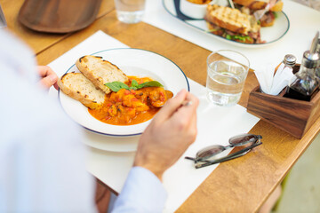 Person eating Livorno fish stew with toast