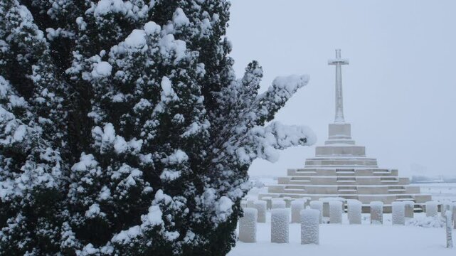 Trees and Cross of Sacrifice covered with snow : unusual image of Tyne Cot british military cemetery in Belgium