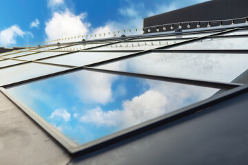 Black metal framed glass roof panels reflecting the outside world