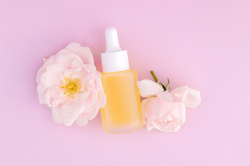 bottle of vitamin C antioxidant serum on a pink background with rose flowers. The concept of skin care at home.