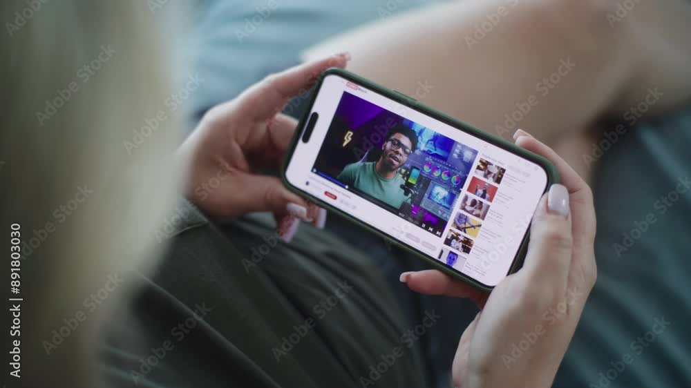 Poster close up of caucasian woman watching video about color grading using mobile phone while lying on sof