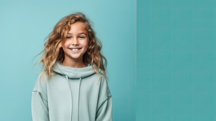 Fototapeta premium cheerful young young girl in clothes, simple teal background color for copy text space, wide screen for ads and banners