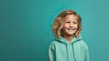 cheerful young young child in clothes, simple teal background