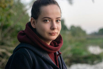 A Portrait photo of a beautiful girl in a green background in nature with tree and leaf and river.