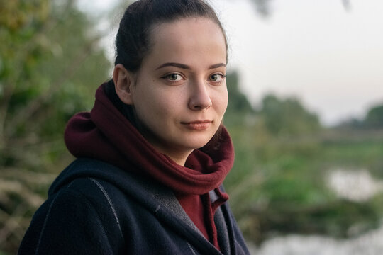 A Portrait photo of a beautiful girl in a green background in nature with tree and leaf and river.