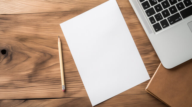 An empty blank white vertical resume paper document mockup template from a top view on a minimalist wooden office desk, placed next to an elegant laptop notebook with a pencil lyin