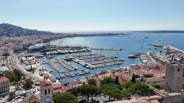 Drone view of Cannes, France, with marina boats, cruise ships, a historic church, and the stunning C&ocirc;te d'Azur coastline along the Mediterranean Sea.
