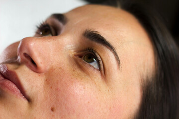  Close-up of a woman's face with a calm expression, lying down before a beauty treatment. 