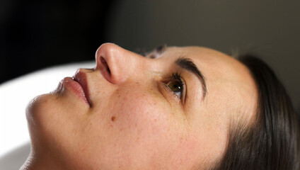  Close-up side profile of a woman lying down, relaxing before a beauty treatment. The image...