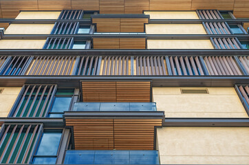 Vertical Perspective of a Tan and Beige Building Wall with Wooden Balconies.