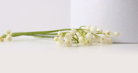 Lily of the valley  flower bouquet on white podium. Light beige background. Minimal empty display product presentation scene. © Liliia