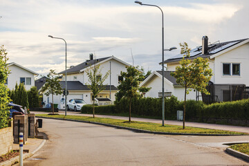 Picturesque European village with modern villas, asphalt road, and solar panels on rooftops,...