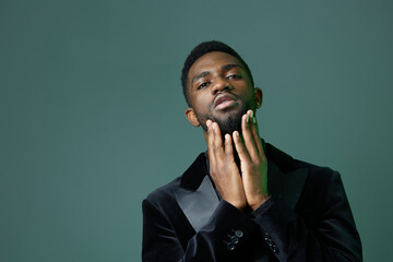 Pensive man contemplates with hands on face and chin against vibrant green background