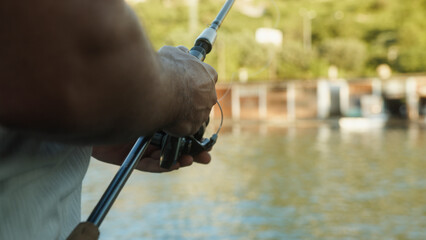 Close-up of a fisherman twist reel with fishing line on a rod on shore. Fishing in the sea outdoors	
