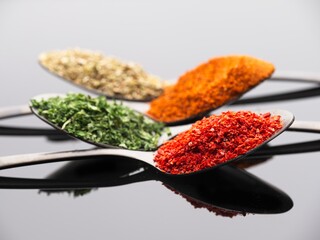 Various spices on white reflective surface.
